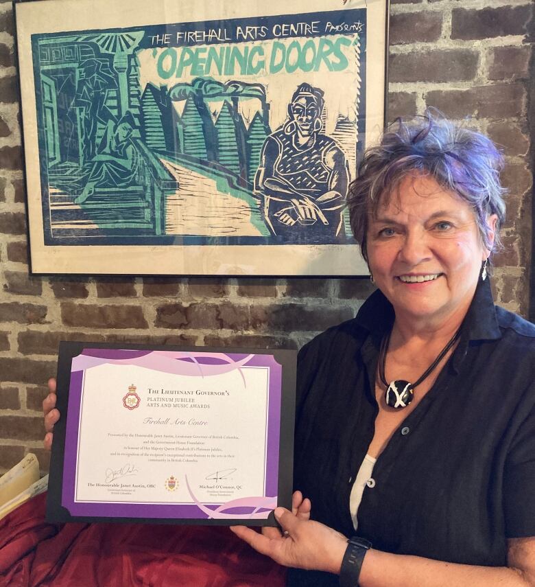 A woman holds up a purple cerificate.