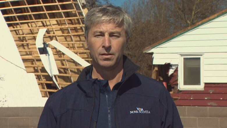 A man stands in front of a seriously damaged building.