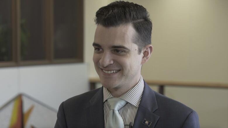 Matthew Shoemaker smiles, wearing a suit and tie. 