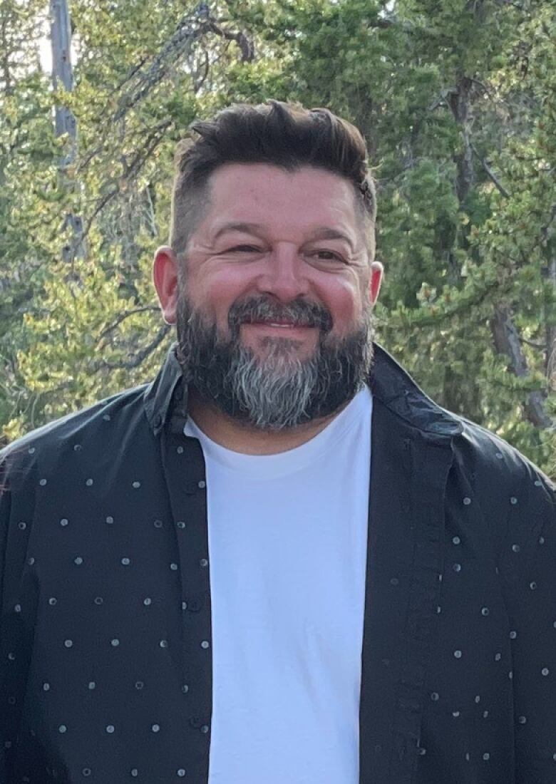 Man with beard smiling looking off into the distance.