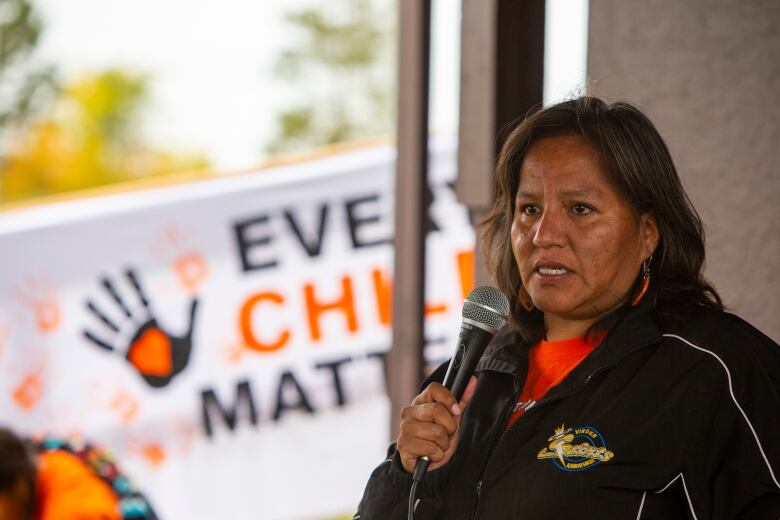 A woman with tears in her eyes hold a mic.