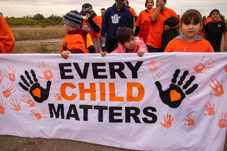 Children hold a sign that says 