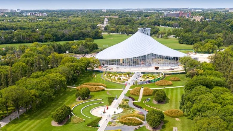 An aerial shot shows a large building surrounded by trees