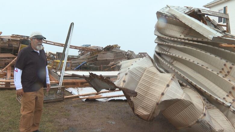 Sam Turkington next to the twisted remains of a steel storage shed.