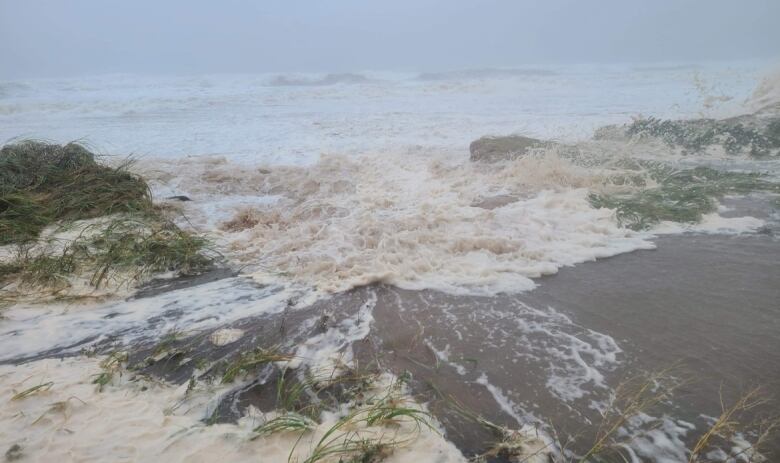 Big waves crashing on a beach in stormy weather.