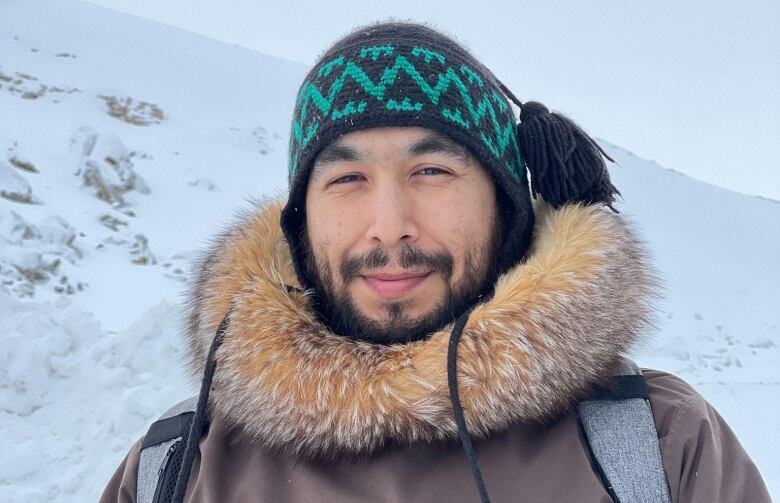 Picture of a man wearing winter clothes and standing outside in the snow.