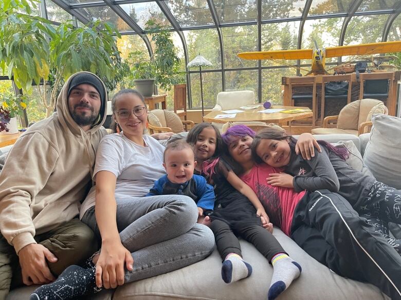 Happy family of six crashed on a couch. 