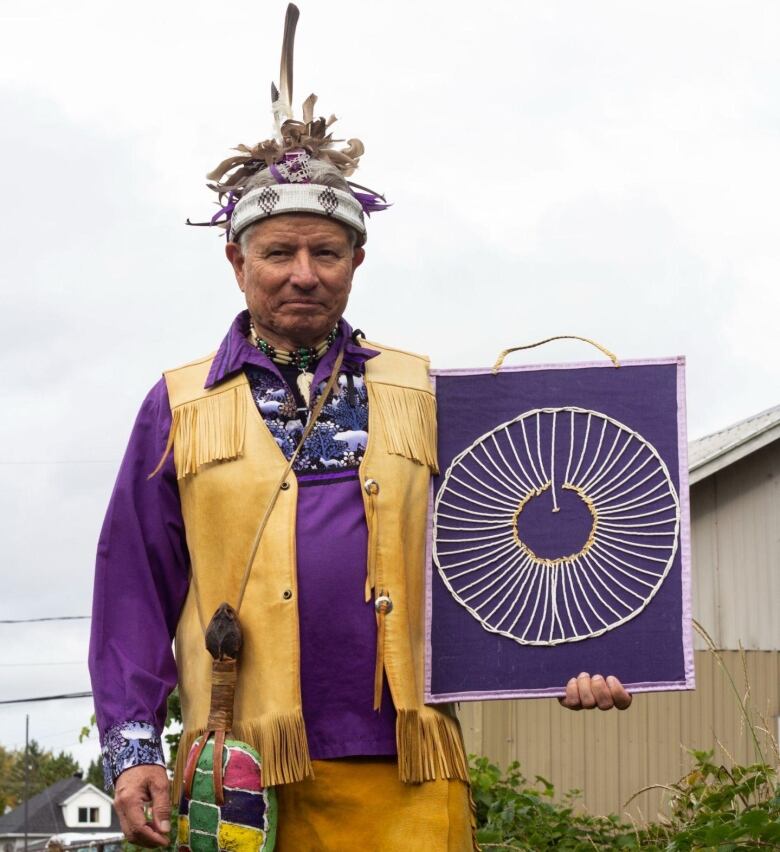 A man dressed in fringed deerskin and a purple shirt.