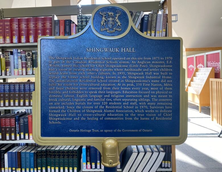 Blue and gold historic plaque standing in front of book shelves in a library