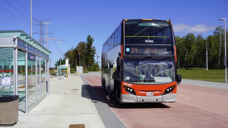 A person gets on a red bus at a station.