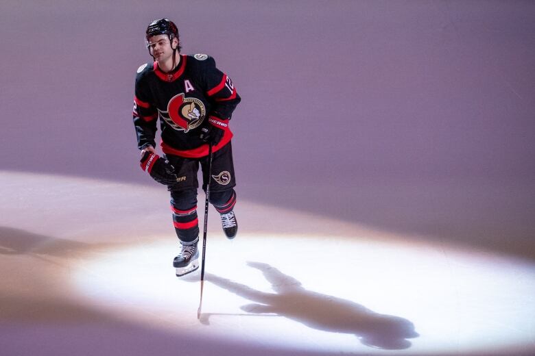 A hockey player skates under a spotlight after a game.