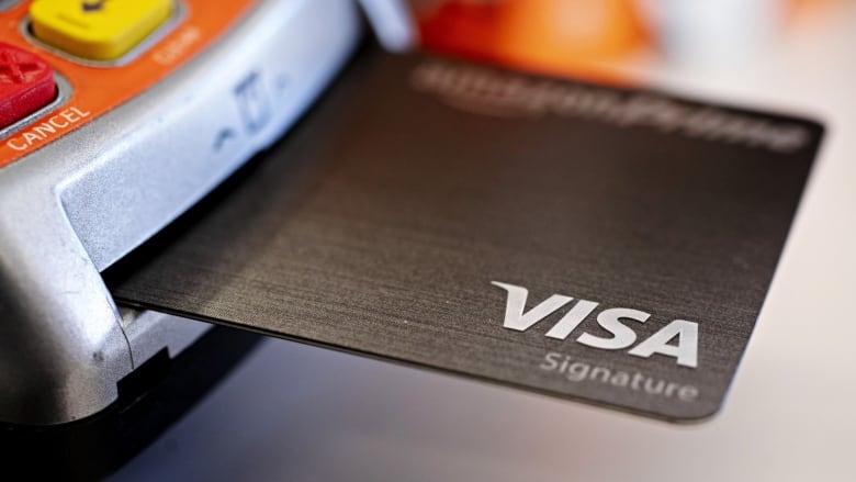 A Visa credit card sticking out of an Interac machine. 