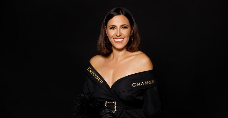 A woman smiles at the camera wearing a garment that says Empower Change around the neckline.