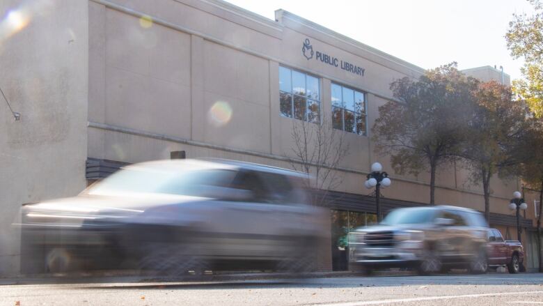 Cars drive past a building.