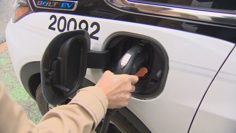 Someone plugs a charging cable into an electric vehicle.