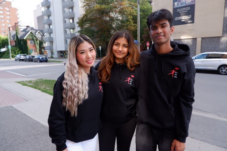 An image of three young people wearing black hoodies.