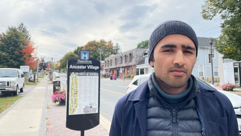 A young man stands in front of a sign. 