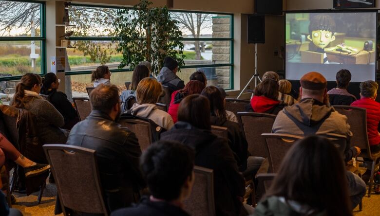 Audiences watch an animated movie.