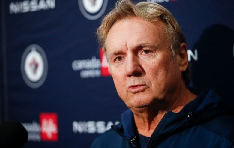 A head shot of a man against a Winnipeg Jets logo.