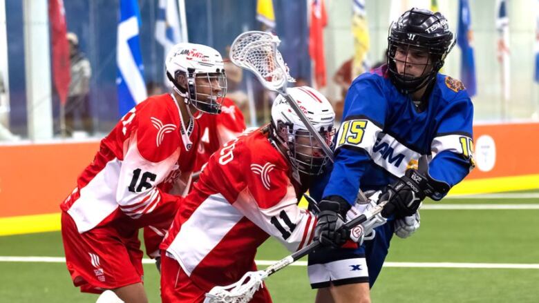 Two lacrosse players in red, one in blue.