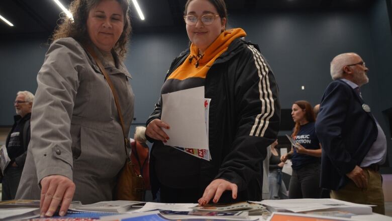 Two women reached for a table covered in election pamphlets