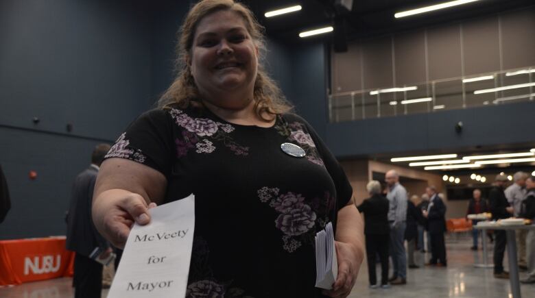 Leslie McVeety reaches towards the camera with a white pamphlet that reads 'McVeety for mayor'