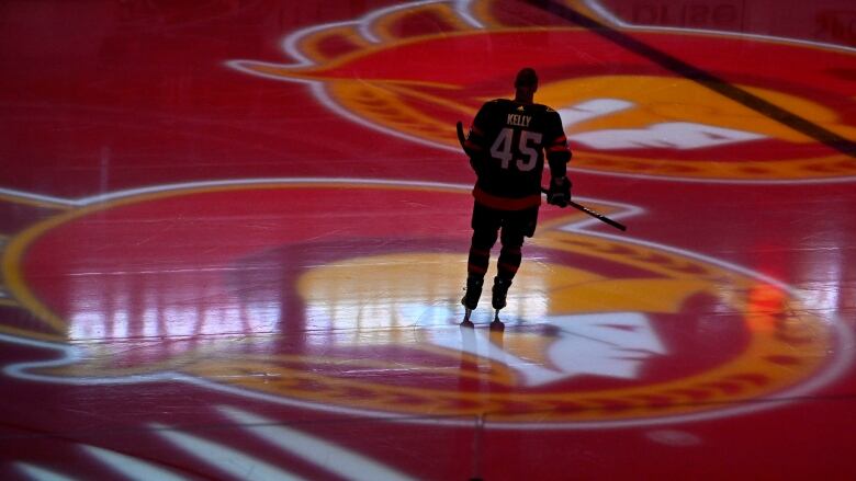 A hockey player on a darkened rink with projections of the Ottawa Senators logo.