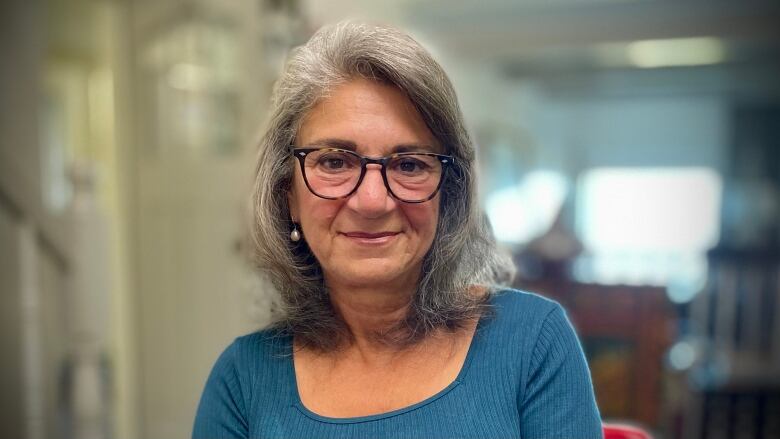 A woman with glasses smiles into the camera. 