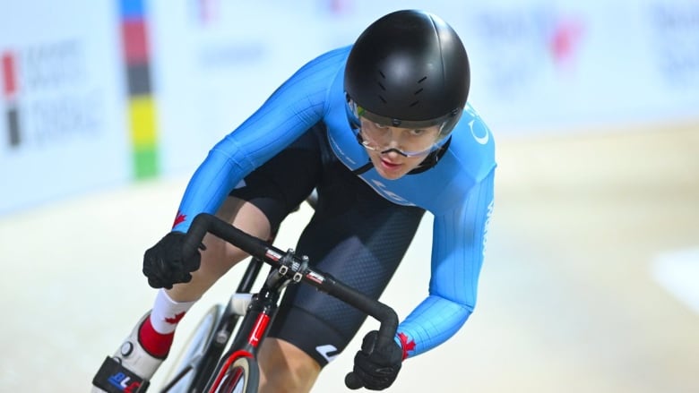 Closeup of a woman in tight blue attire and her bike as she leans into a corner while racing on a track.