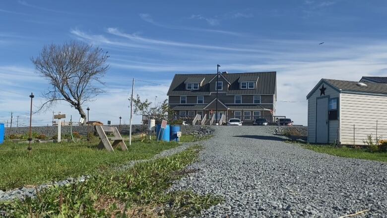 A three-storey building sits at the end of a long gravel driveway.