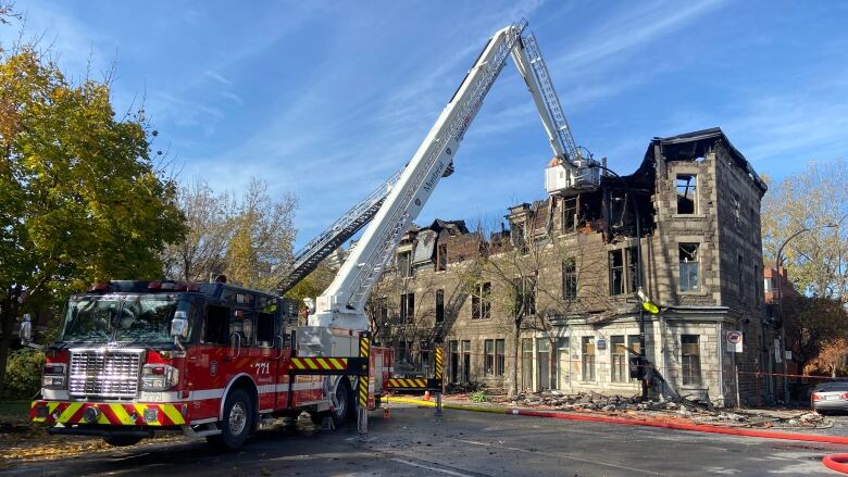 A fire truck is parked in front of a greystone. 