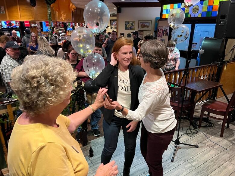 A woman is congratulated by two other people at a party.