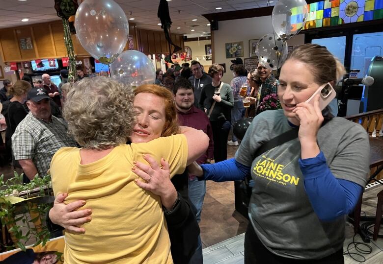 Two people embrace at a party with balloons.