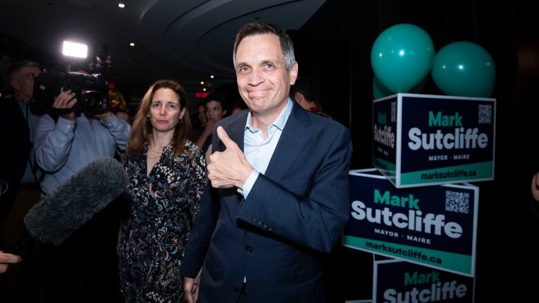 A politician gives the thumbs-up to a photographer at a party.