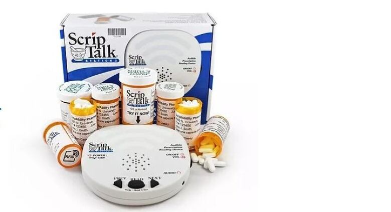 A ScripTalk reader is seen with an assortment of prescription bottles and the box it is sold in.