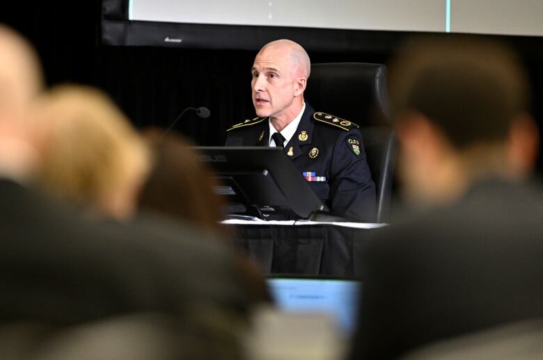 A police officer in uniform speaks at a microphone.