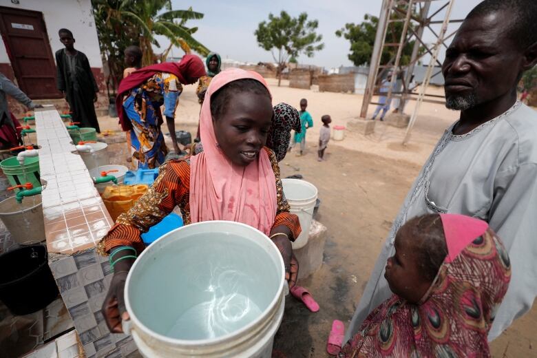 A girl holds a bucket she filled at the water at an IDP camp in Nigeria.