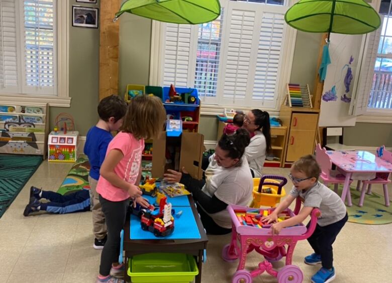 Children play with toys in a classroom.