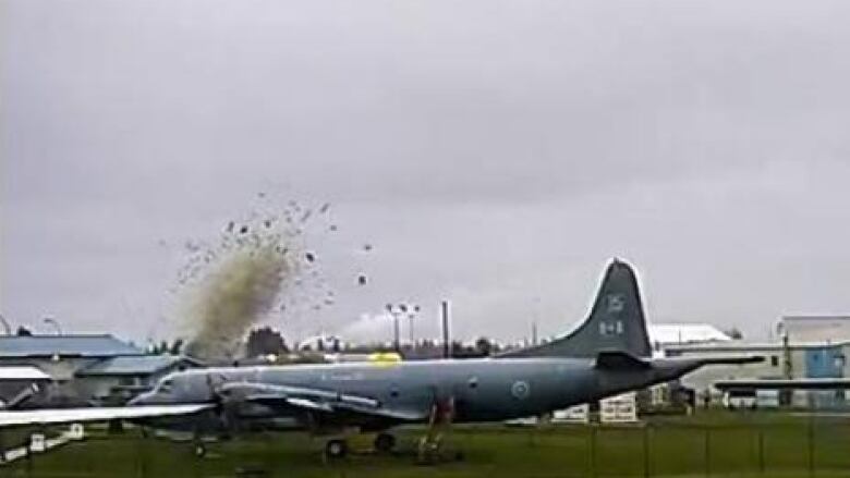 A large explosion is visible behind a military aircraft.