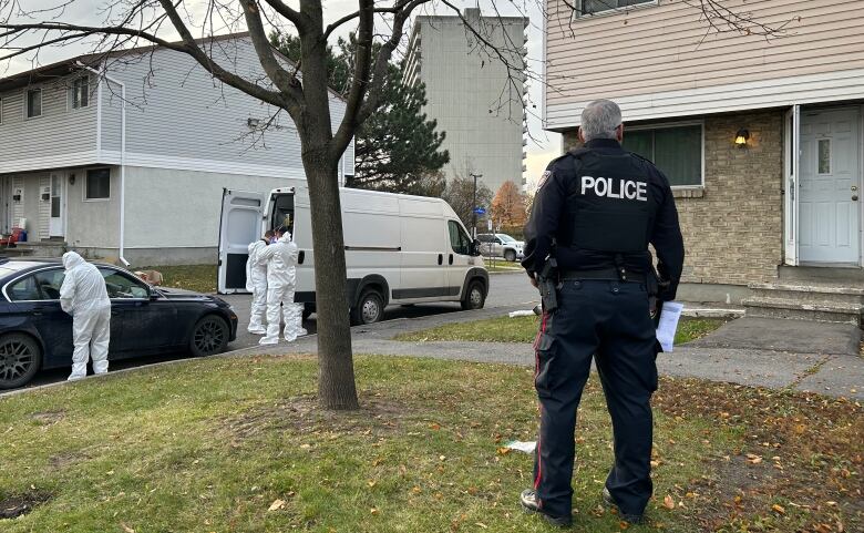 A police officer stands outside a house.