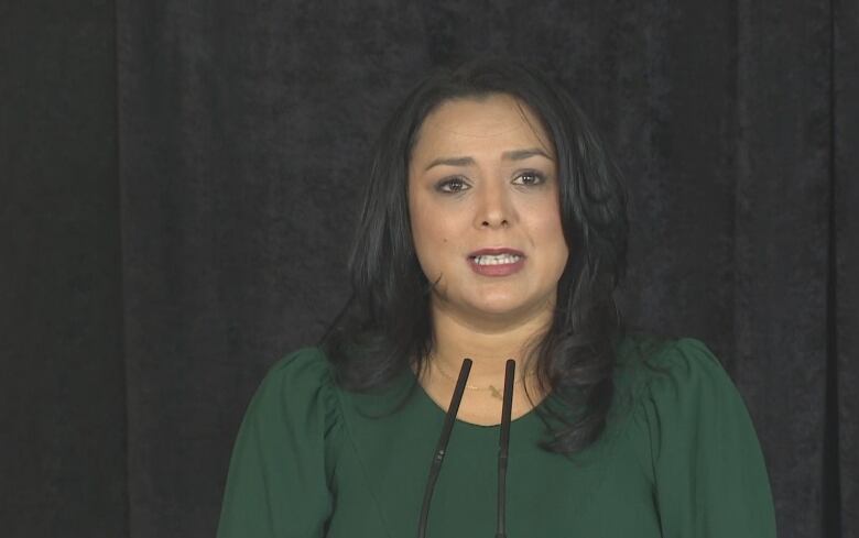 Doctors of B.C. president Ramneek Dosanjh stands at a podium during a press event on Monday, Oct. 31. She has shoulder-length black hair, wears a dark green blouse and is photographed from the chest up.