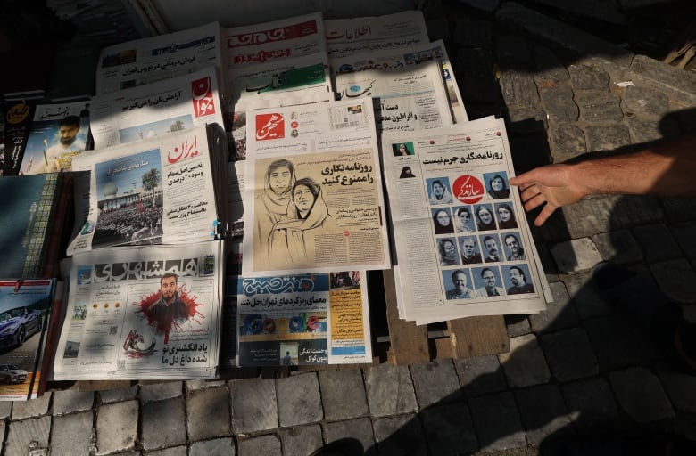 Several Iranian newspapers laid out on the ground.