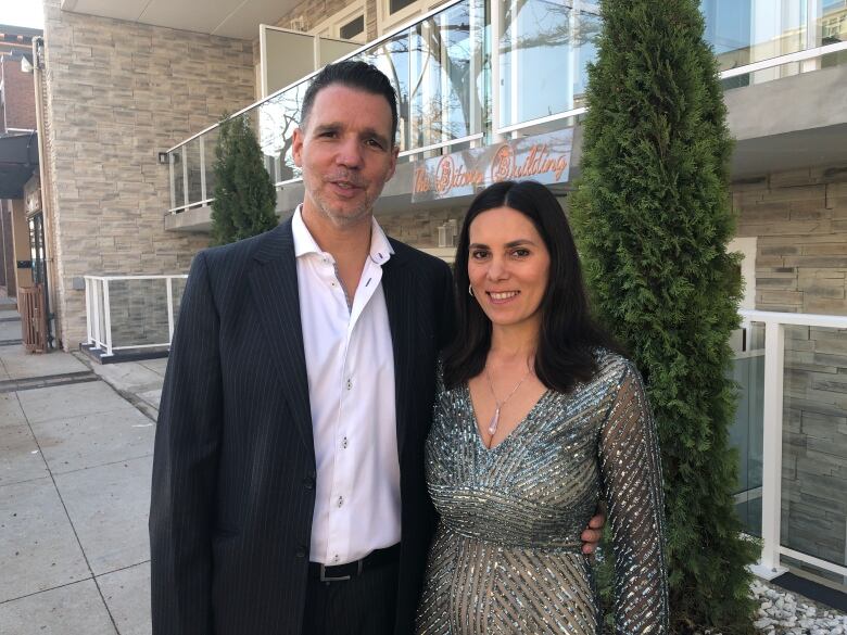 Man and woman smile outside building