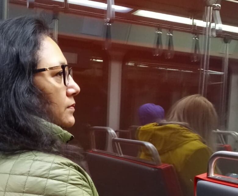 A woman sits on a seat in a Calgary train. 