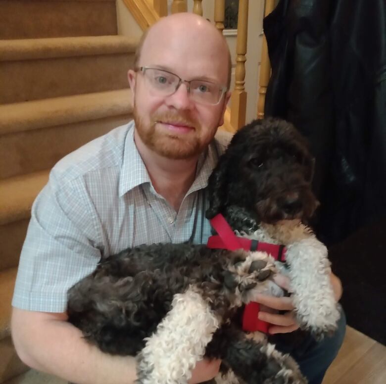 A man holds a small dog in his arms.