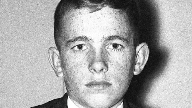 A black and white picture of a teenage boy wearing a suit.