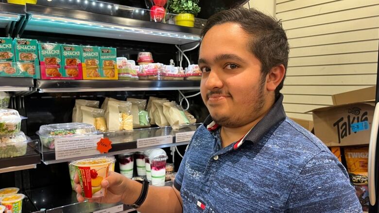 A young man holding a fruit cup in front of a food bank