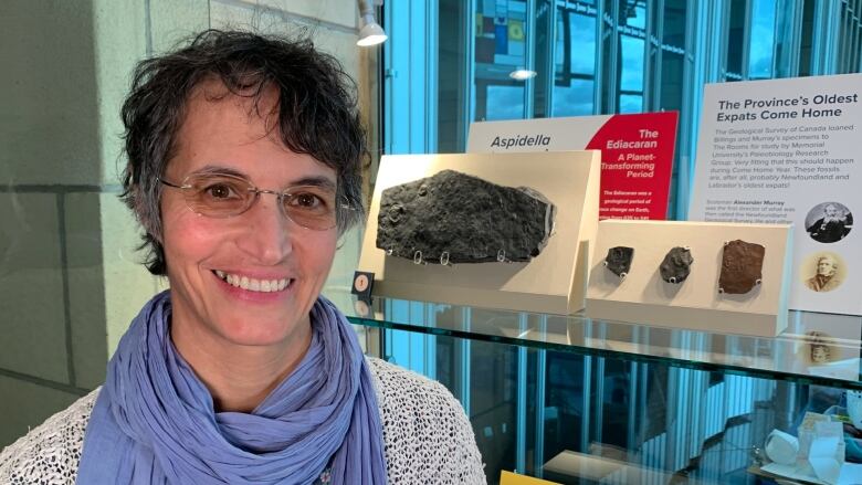 A woman stands in front of a display of fossils at The Rooms.