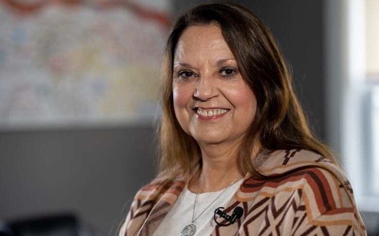 Chief Darlene Bernard in the meeting room at the Lennox Island First Nation band office. She is smiling for the photo with long brown hair, a brown sweater and a white shirt under. 