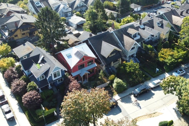 A red single-family home stands in a row of houses.